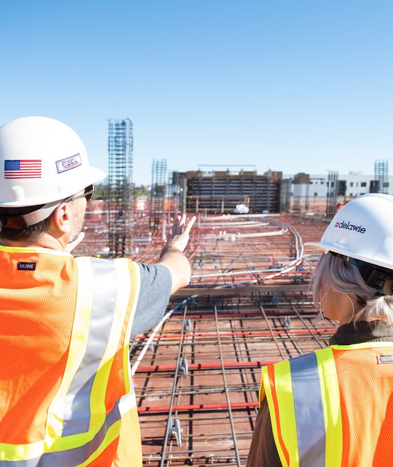 Two site supervisors in hi-vis reviewing progress on a live construction site