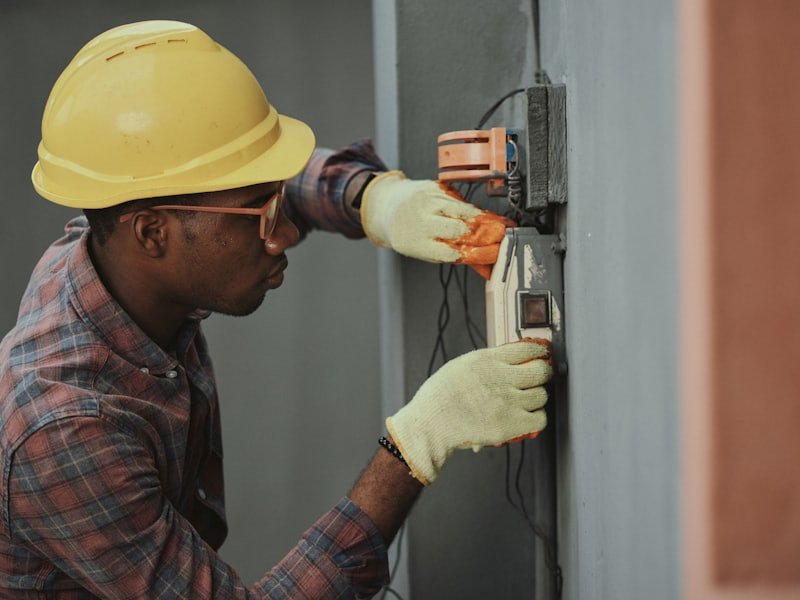 An electrician in a hard hat working on a distribution board